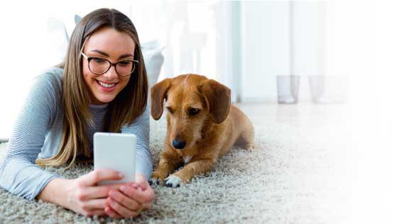Imagen de una mujer acompañada de su mascota observando su teléfono móvil
